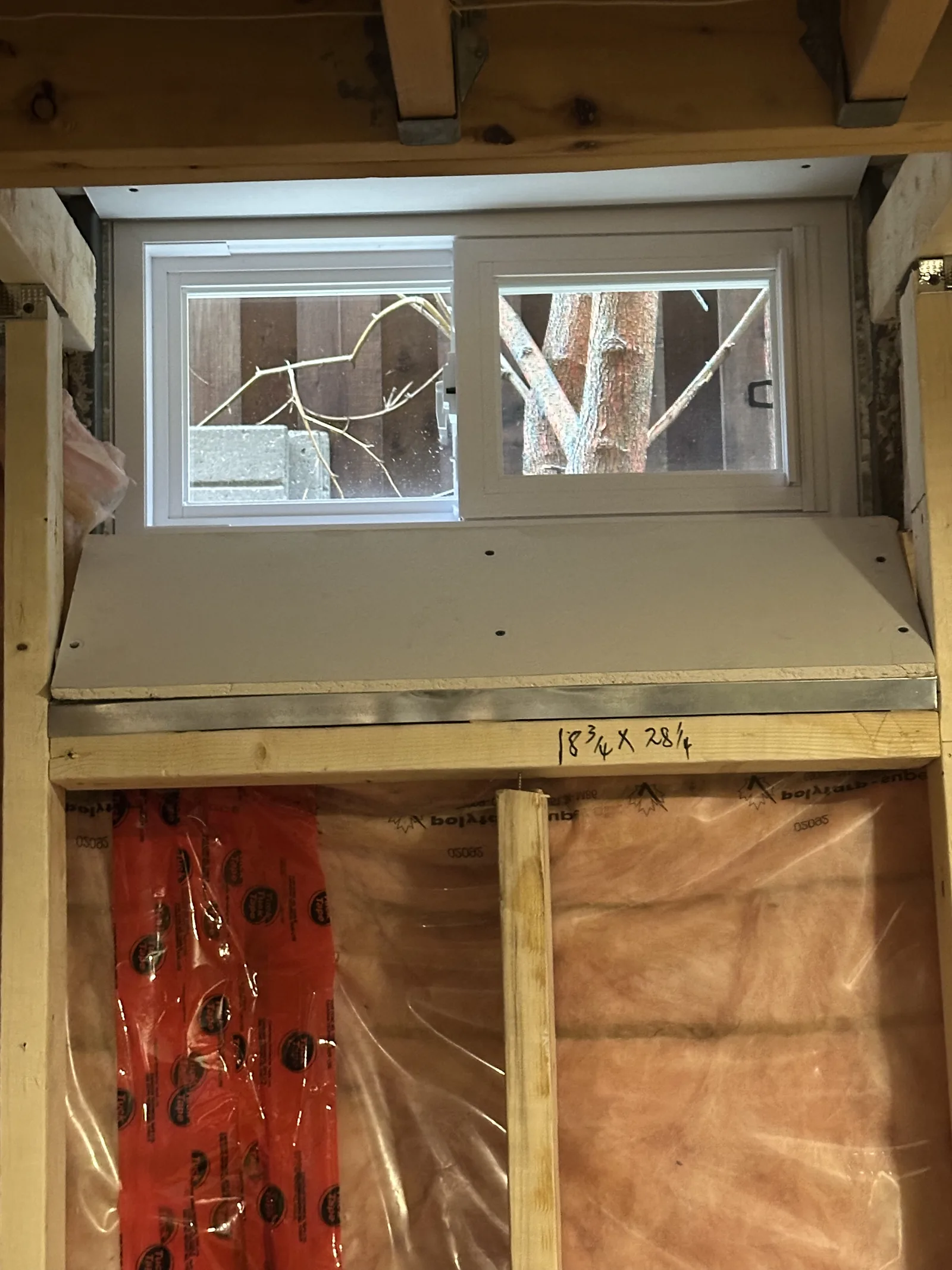 New egress window set into fresh framing in a basement build